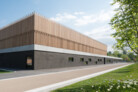 Das von a+r Architekten entworfene und bereits zweifach ausgezeichnete Gebäudeensemble aus Mehrzweck- und Dreifeldsporthalle wird durch einen Fassadensockel verbunden. Im oberen Bereich sind die beiden Hallenkörper mit einer detailliert ausgeführten Holzlattung verkleidet und bilden eine Art „abstrakten Wald“ aus Kanthölzern. | © Marcus Ebener