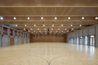 In der Mehrzweckhalle entschieden sich a+r Architekten für eine Akustikwandbekleidung aus kesseldruck imprägniertem Lärchevollholz. Für das Deckentragwerk kommen Leimholzbinder und eine Brettstapeldecke zum Einsatz. | © Marcus Ebener