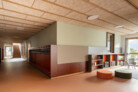 Kindergarten, Erdgeschoss (L 00), Garderobe und Lesebereich. Möbel: Garderobe und Bücherregale aus MDF nach Maß - Entwurf MoDusArchitects - hergestellt von Gampenrieder srl; Hocker Noo.Ma - mod. Folk pouf - Wide. | © Marco Cappelletti