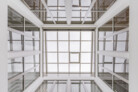 Der beeindruckende Blick aus einem der Atrien nach oben auf das BA-Verglasungssystem von Velux Commercial zeigt, dass das Dach quasi komplett zum Himmel geöffnet wurde. | © Velux Commercial